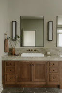 Bathroom vanity with wooden cabinets, marble countertop, and large mirror.